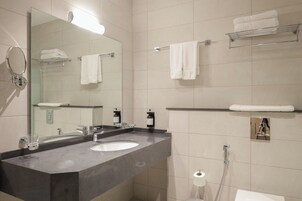 Un baño moderno con dos lavamanos, un espejo grande, toalleros y un dispensador de papel higiénico.