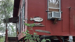 Un bâtiment rouge orné d’une décoration représentant un poisson, avec des places assises à l’extérieur et un escalier menant à une terrasse.