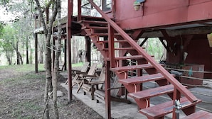 Une structure rustique en bois, dotée d’un escalier, de bancs en bois et d’une petite table.