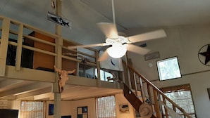 Un intérieur à plusieurs niveaux, doté d’un ventilateur de plafond, d’une enseigne indiquant un restaurant de poisson et d’un panneau d’accueil pour les clients.
