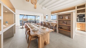 Een moderne keuken met een groot kookeiland, hanglampen en uitzicht op buiten.