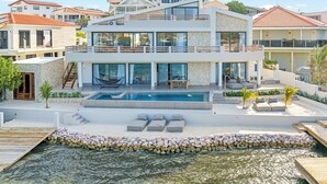 Een modern herenhuis met twee verdiepingen, een zwembad, terras en uitzicht op zee.