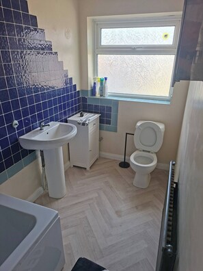 Un baño con lavamanos, inodoro y ventana.