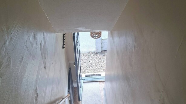 Una escalera que lleva a un espacio exterior con vista a un edificio y una lámpara colgante.