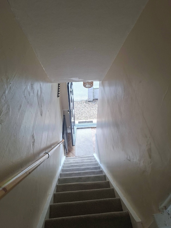 A staircase leading to an outdoor area with a view of a building and a hanging light fixture.