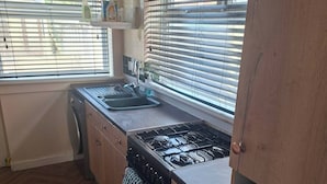 Cocina con estufa a gas, pileta y armarios de madera.