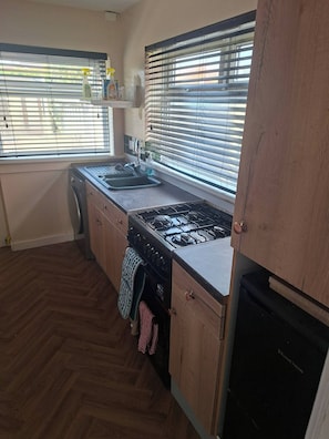 A kitchen with a gas stove, sink, and wooden cabinets.