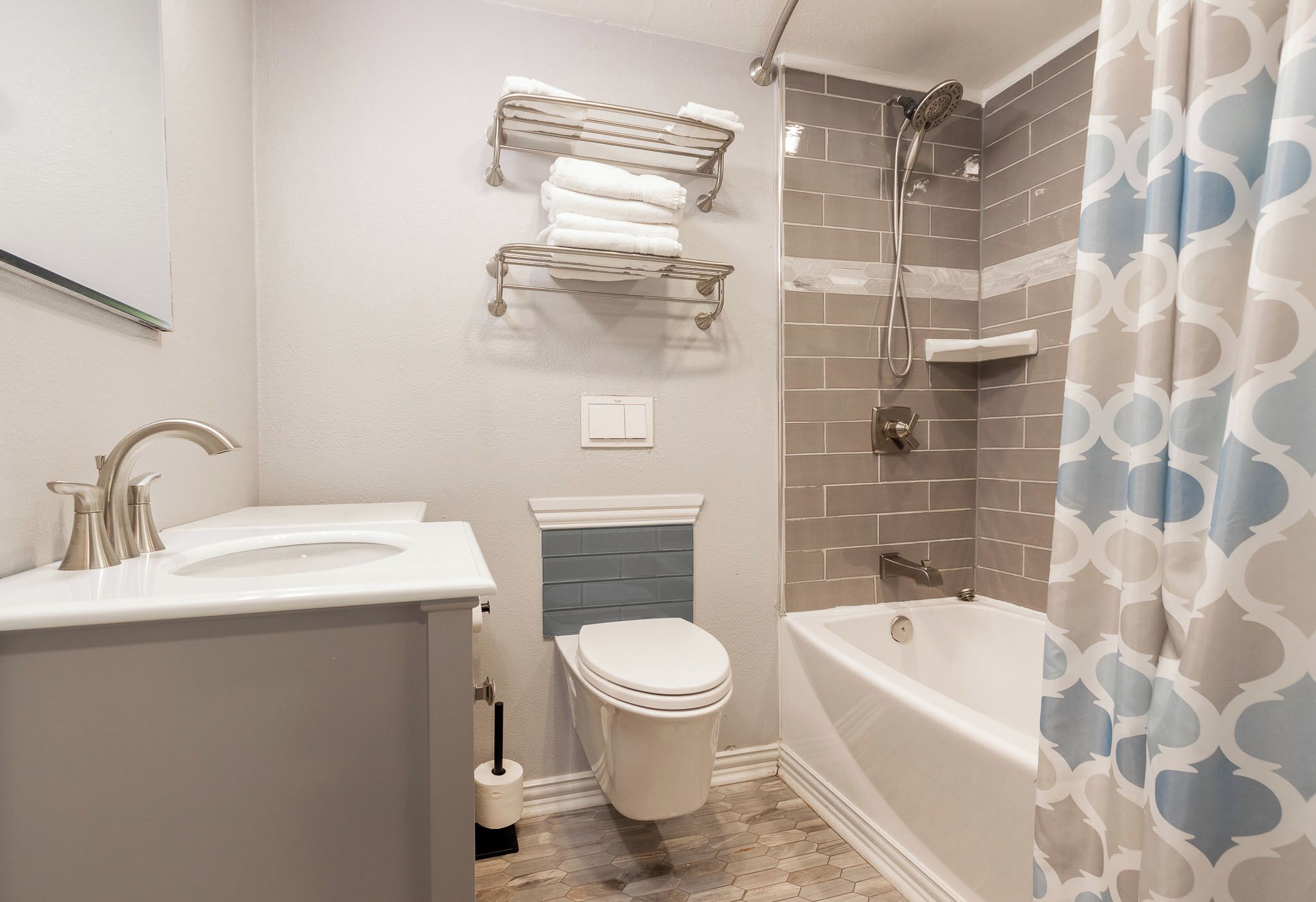 Un baño con inodoro, lavamanos, ducha y toalleros.