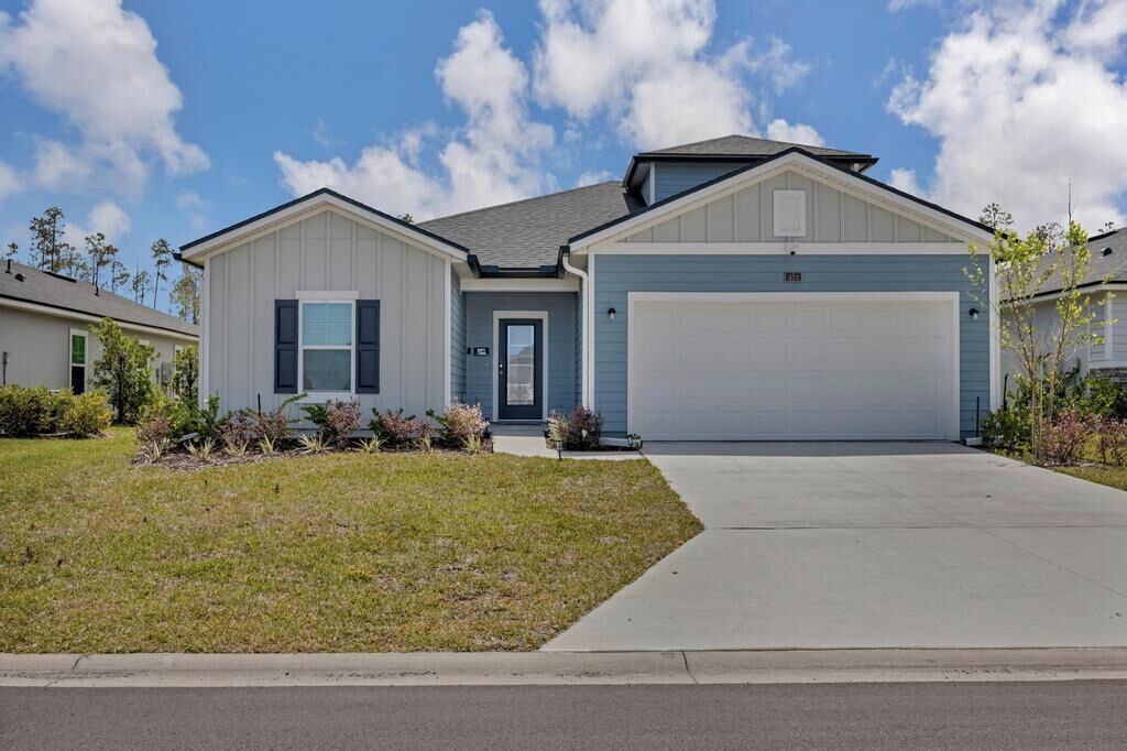 A modern two-story house with a garage, a front lawn, and a clear sky.