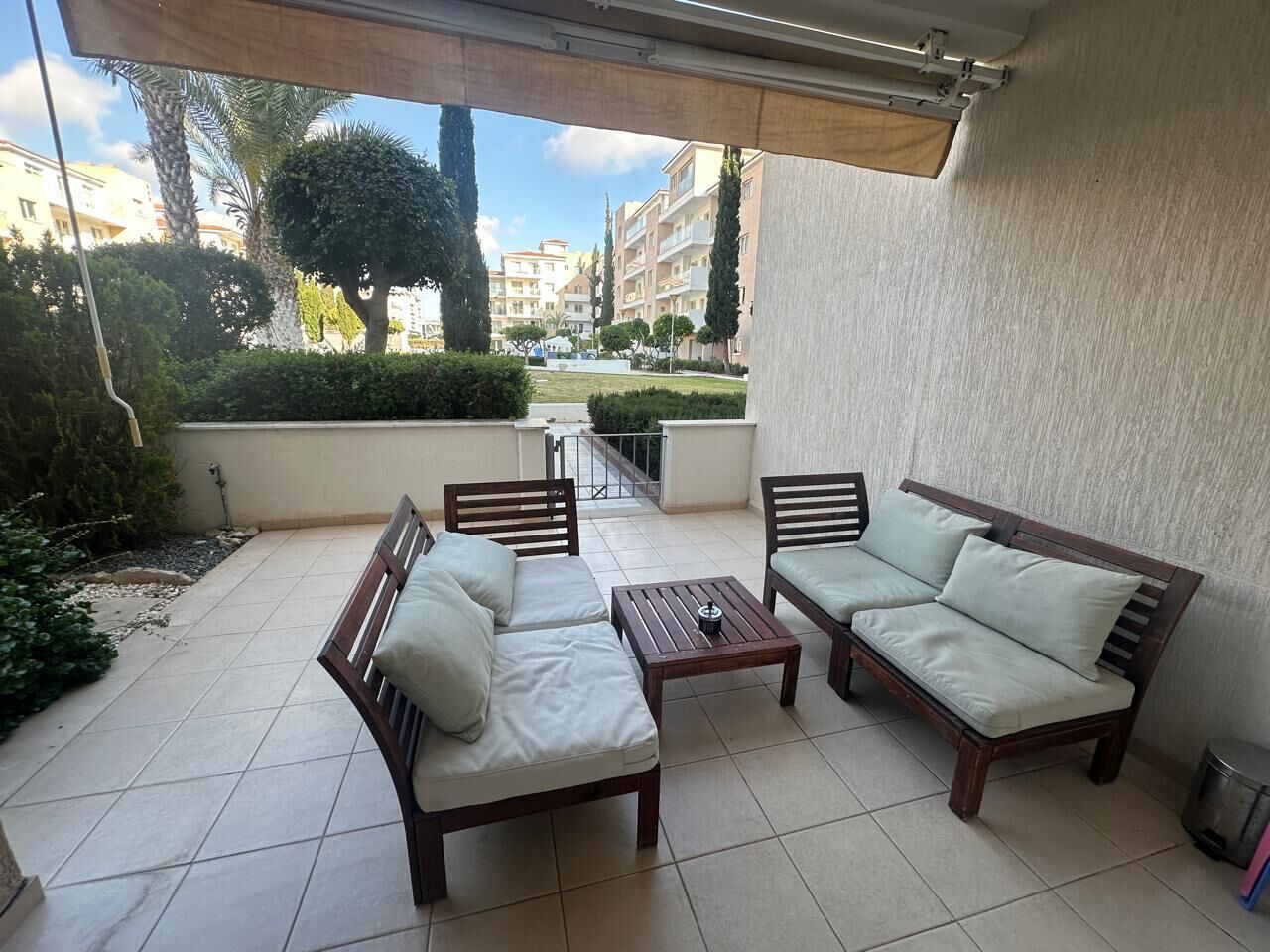 A covered outdoor seating area with two sofas and a table, surrounded by a tiled patio.. Elysia Park Pafos