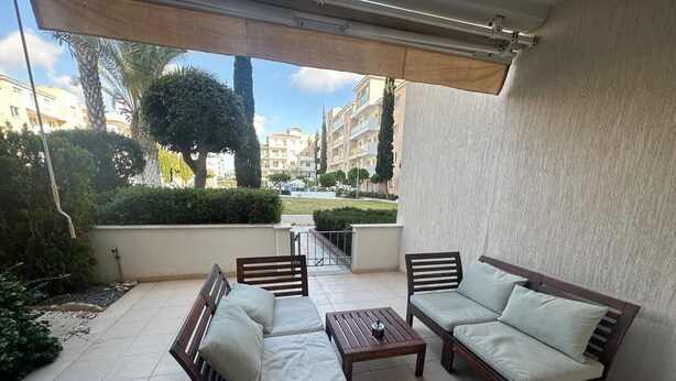 A covered outdoor seating area with two sofas and a table, surrounded by a tiled patio. - Elysia Park Pafos (Paphos)