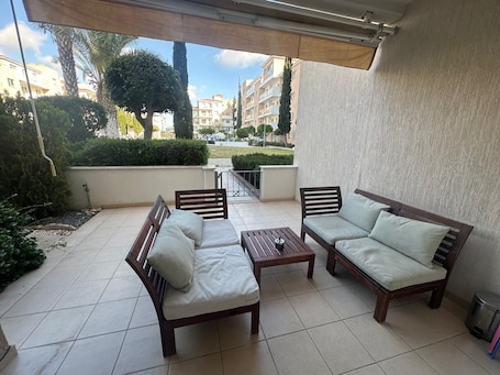 A covered outdoor seating area with two sofas and a table, surrounded by a tiled patio.. Elysia Park Pafos