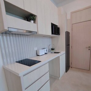 A compact kitchen with a microwave, refrigerator, and a toaster on the counter. - 2-bedroom condo in brilliant Muang Pattaya with AC and gym access  Stream room (Muang Pattaya)