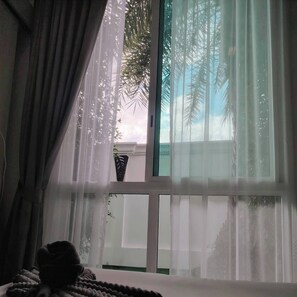 A room with a large window, a bed, and a plant on the windowsill. - 2-bedroom condo in brilliant Muang Pattaya with AC and gym access  Stream room (Muang Pattaya)