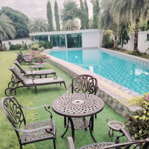 A pool area with lounge chairs, a table, and a building with glass doors. - 2-bedroom condo in brilliant Muang Pattaya with AC and gym access  Stream room (Muang Pattaya)