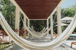 A hammock under a wooden pergola in a covered outdoor area with lounge chairs and umbrellas. - Modern Jungle Escape - Selva Escondida 2
Family sized condo with pool and gym (Puerto Morelos)