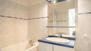 A bathroom with a bathtub, a sink, and a mirror.