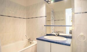 Un baño con bañera, lavamanos y espejo.