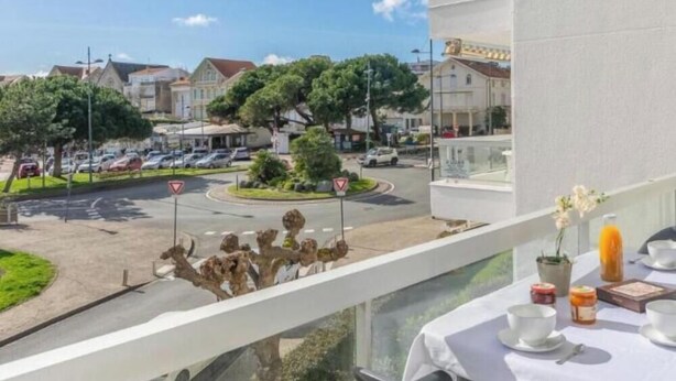 A balcony with a table set for breakfast, overlooking a roundabout with traffic signs and parked cars.
