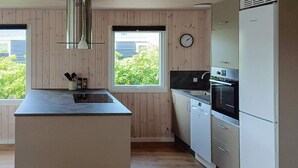 Una cocina moderna con una isla central, electrodomésticos integrados y vistas a zonas verdes.