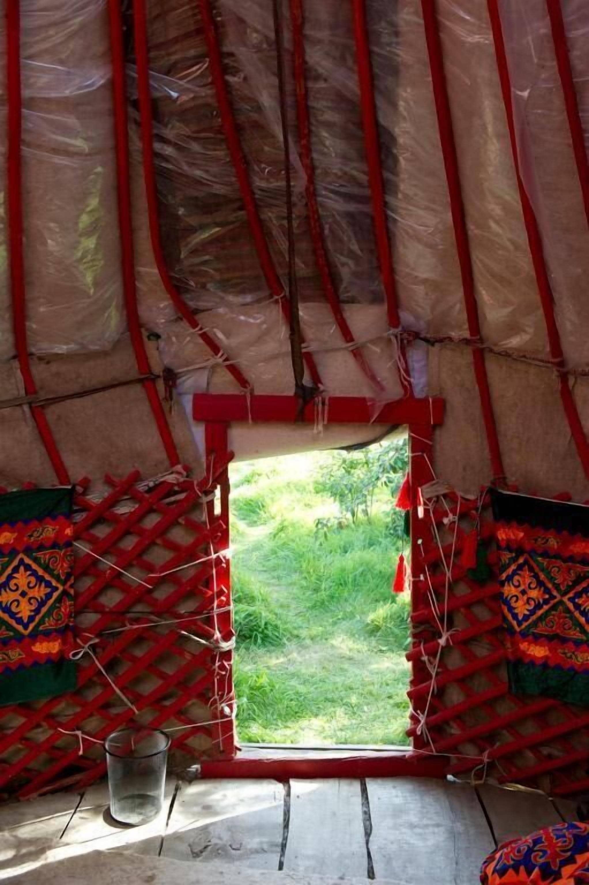 A tent with a window, a metal bucket, and a patterned cushion.