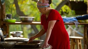 A person cooking outdoors with cooking utensils and a pot on a table. - Belzhan Yurt Lodge (Grigorevka)