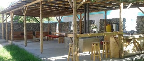 Un espacio al aire libre cubierto con pared de piedra, bancos de madera y una zona de bar.