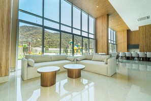 Ein modernes Interieur mit einem großen Fenster, einem Ecksofa und zwei runden Holztischen.