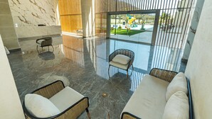 Eine geräumige Lobby mit Marmorboden, Korbmöbeln und Blick auf einen Spielplatz im Freien.