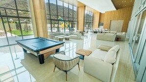 Ein geräumiger Innenbereich mit Billardtisch, Sofas und Blick auf einen Spielplatz durch große Fenster.