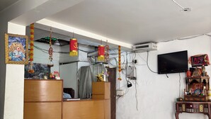 A room with a wooden desk, a television mounted on the wall, and a patterned floor. - Staylo Jaggannath Stays (New Delhi)