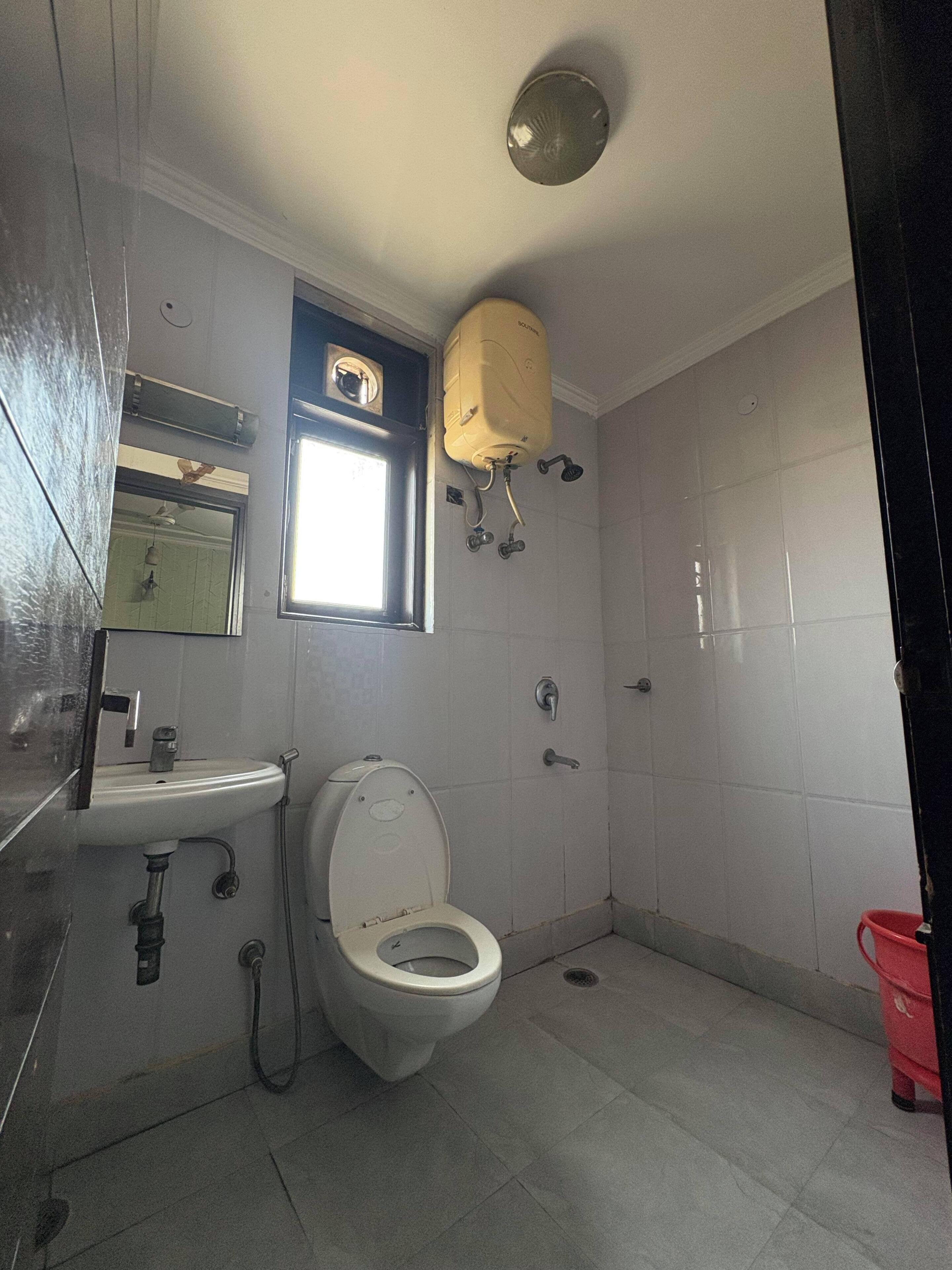 A bathroom with a toilet, sink, and a window.