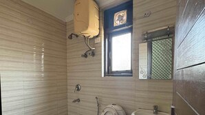 A small bathroom with a toilet, sink, and a window. - Staylo Jaggannath Stays (New Delhi)