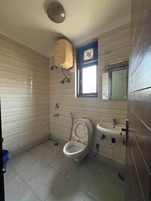 Une petite salle de bain avec des toilettes, un lavabo et une fenĂȘtre.
