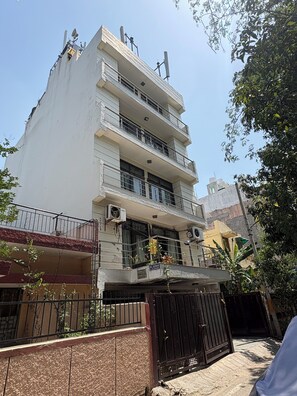 A multi-story residential building with balconies, air conditioning units, and a gated entrance. - Staylo Jaggannath Stays (New Delhi)