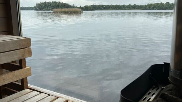 A wooden deck with a bench, a grill, and a view of calm water with a distant island. - Mockelsnas Manor Manor Gardenview Queen Room (Diö)
