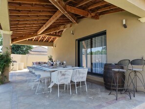 Eine Terrasse im Freien mit Holzboden, einem Esstisch und einem Fass.