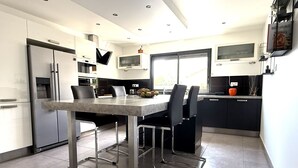 A modern kitchen with a dining table, chairs, a refrigerator, and a window. - 12-Person Villa A/C Heated Pool office close Aix Provence (Salon-de-Provence)