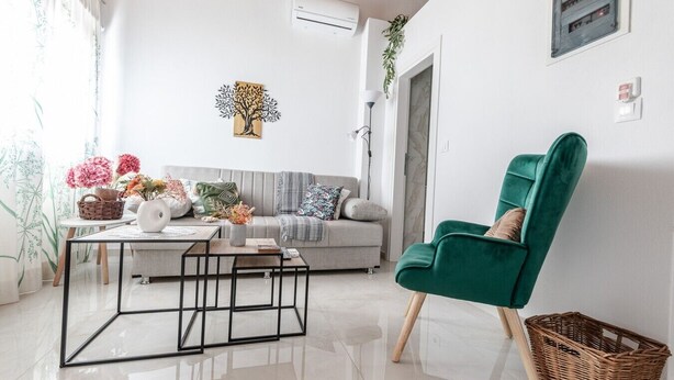 A living room with a sofa, a green armchair, a coffee table, and a wall-mounted air conditioner. - Phaedrus Living: Skiathos Luxury Residences Green (Skiathos)
