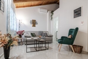 A modern living room with a sofa, coffee table, and a green armchair. - Phaedrus Living: Skiathos Luxury Residences Green (Skiathos)