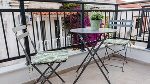 A balcony with two foldable chairs, a small round table, and a potted plant. - Phaedrus Living: Skiathos Luxury Residences Green (Skiathos)