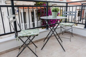 A balcony with two foldable chairs, a small round table, and a potted plant. - Phaedrus Living: Skiathos Luxury Residences Green (Skiathos)