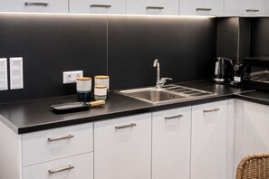 A modern kitchen with a black countertop, stainless steel sink, and white cabinets. - LIV - Upscale Athenian Apartment 4B (Athens)