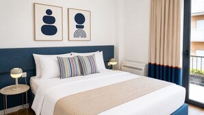 Ett hotellrum med en stor säng, två sängbord, en väggmonterad luftkonditioneringsanläggning och utsikt genom ett fönster med gardiner.