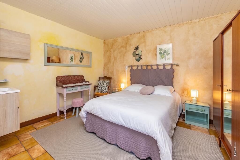 A bedroom with a bed, bedside tables, a dresser, a mirror, and wall art.