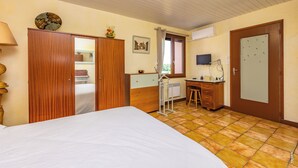 Ein Schlafzimmer mit Bett, Holzschrank, Schreibtisch, Stuhl und einem Fenster mit Vorhängen.