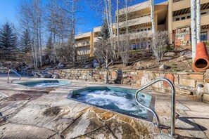 Ein Wellnessbereich mit zwei Whirlpools, Steinwegen und einer Steinwand.
