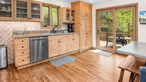 Eine moderne Küche mit Holzausstattung, einem Geschirrspüler und einem Essbereich mit Tisch und Stühlen.