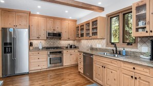 Eine moderne Küche mit Holzschränken, Edelstahlgeräten und einer Arbeitsplatte aus Granit.