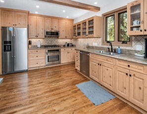 Eine moderne Küche mit Holzschränken, Edelstahlgeräten und einer Arbeitsplatte aus Granit.